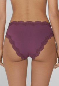 Burgunder Unterwäsche mit Spitzendetails und gewelltem Design. Glattes Material, mittelhoher Schnitt und nahtloser Rücken für ein angenehmes Tragegefühl.
