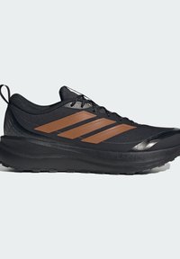 Chaussure de sport noire avec semelle épaisse, trois bandes marron sur le côté, design à lacets et languette au talon, vue en profil droit.