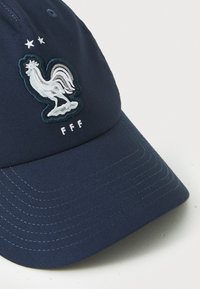 Casquette de baseball marine avec un tissu texturé, logo de coq blanc brodé et "FFF" sous deux étoiles. Visière courbée et sangle ajustable.