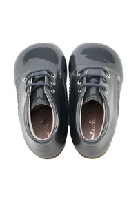 Zapatos de charol gris oscuro con puntera redondeada, cordones y detalles perforados en los laterales. Acabado suave y brillante con plantillas de color claro.