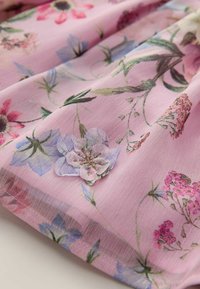 Einen blumigen, rosa Stoff mit blauen und lila Blumen, die filigrane Details aufweisen. Leichte, durchsichtige Textur; zarte Stickereien sind sichtbar.