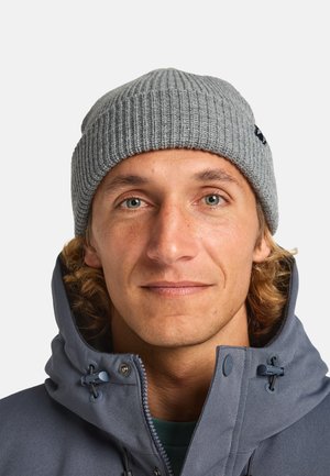 Grijze geribbelde beanie gemaakt van gestructureerde brei-stof, gedragen met een grijze zip-up jas met hoge kraag en verstelbare hardware.