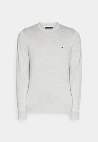 Maglione grigio chiaro a maniche lunghe con collo rotondo, con piccolo logo rosso, bianco e blu di Tommy Hilfiger sul lato sinistro del petto.