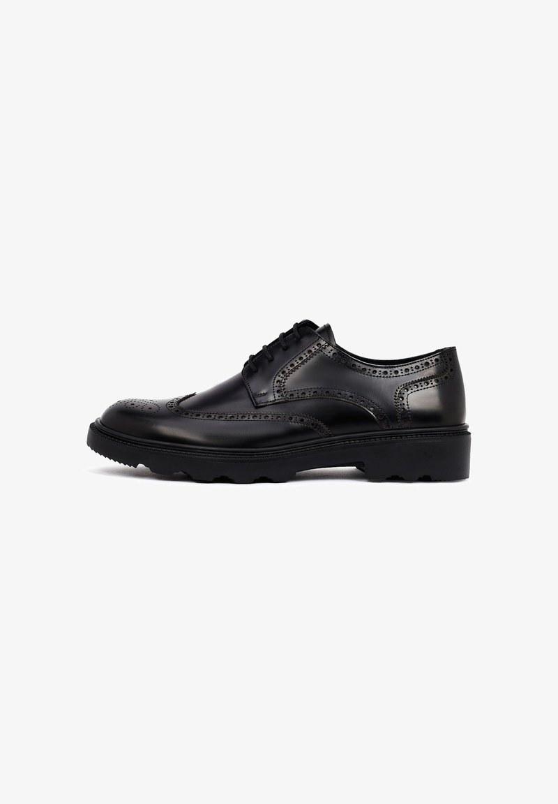 Zwarte leren dresschoenen met een brogue ontwerp, voorzien van geperforeerde accenten en een dikke, gestructureerde rubberen zool. Vetersluiting met een ronde neus.