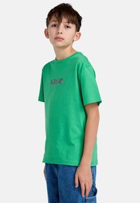 Groene katoenen T-shirt met een ronde hals en korte mouwen, voorzien van een klein meerkleurig grafisch ontwerp op de voorkant.