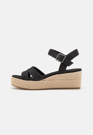 Schwarze, aus gewebtem Stoff gefertigte Wedge-Sandalen mit überkreuzten Riemen, verstellbarem Knöchelriemen und geflochtener Sohle im Jutestil. Gummisohle.