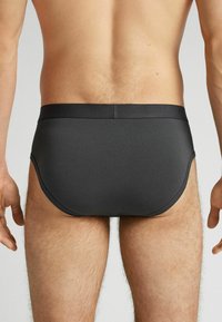 Schwarze Herrenunterhosen mit glatter Textur und elastischem Bund. Das Design bietet eine enge Passform ohne sichtbare Nähte.