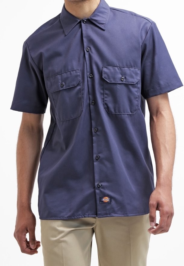 Chemise marine à manches courtes en tissu lisse, dotée de deux poches poitrine, d'une fermeture à boutons et d'un écusson logo sur l'ourlet inférieur.