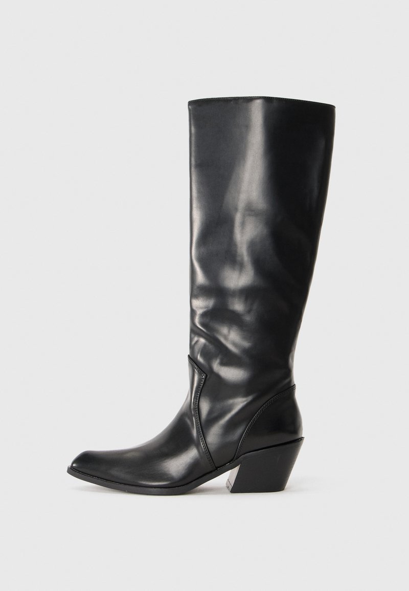 Botte en cuir noir montante jusqu'au genou avec un bout pointu, un talon angulaire et une texture lisse. Présente une subtile couture sur le côté.