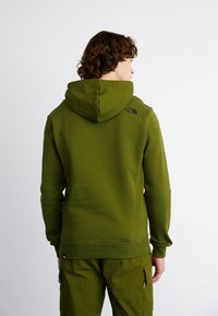 Felpa verde realizzata in tessuto morbido, dotata di cappuccio con cordino, polsini a costine e un piccolo logo nero sulla parte superiore della schiena.