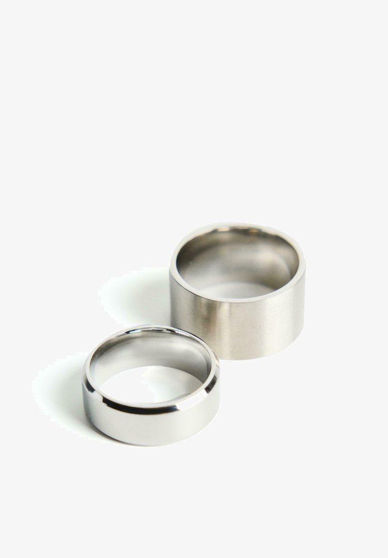 Két gyűrű látható: az egyik egy fényes ezüstgyűrű, keskeny profilú, a másik pedig egy matt ezüstgyűrű, szélesebb profilú.