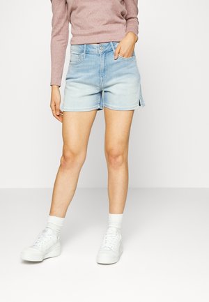 Lichtblauwe denimshorts met een ontspannen pasvorm, gezoomde randen en zijsplitten. Gecombineerd met witte sneakers en een geribbelde top met lange mouwen.