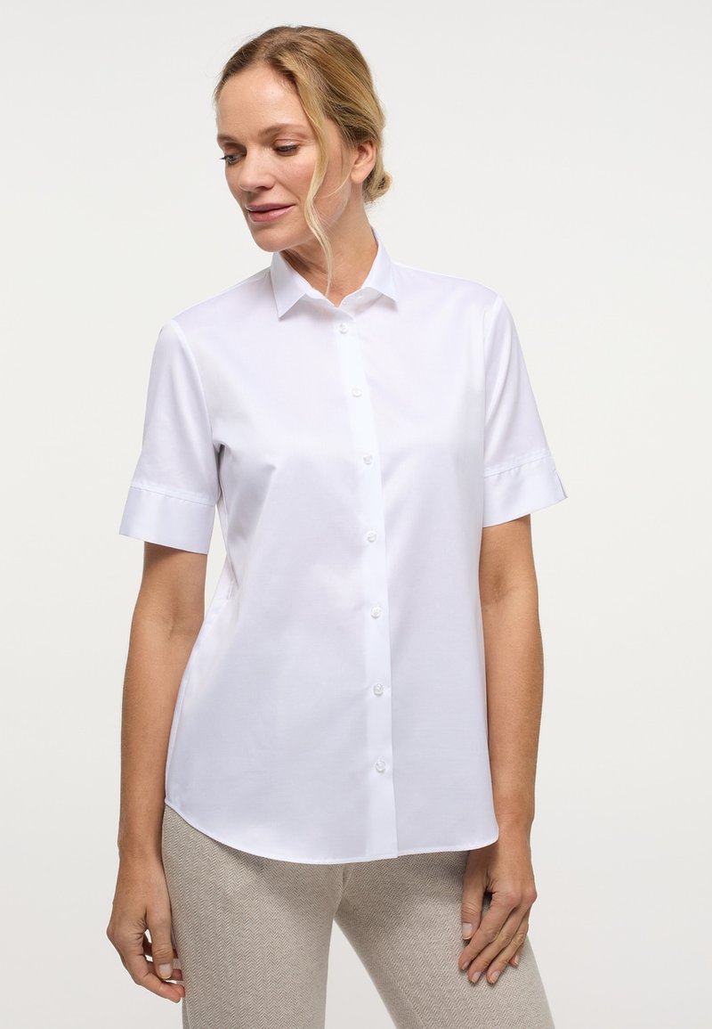 Camicia bianca a maniche corte con bottoni, realizzata in tessuto liscio, caratterizzata da un colletto classico e una vestibilità sagomata con un leggero lucido.