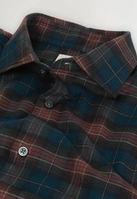 Chemise à carreaux avec des nuances de bleu foncé, marron et bordeaux ; fabriquée en tissu doux avec un col classique et une fermeture à boutons.