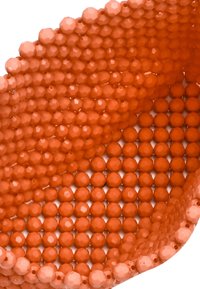 Accessorio arancione realizzato con due tipi di perline; un lato presenta perline tonde, mentre l'altro mette in mostra perline sfaccettate.