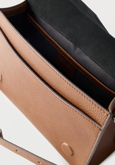 Καφέ δερμάτινη τσάντα χιαστί με υφασμάτινη εσωτερική επένδυση σε μαύρο χρώμα και κλείσιμο με μαγνητικό κουμπί, εμφανίζεται ανοιχτή από πάνω.