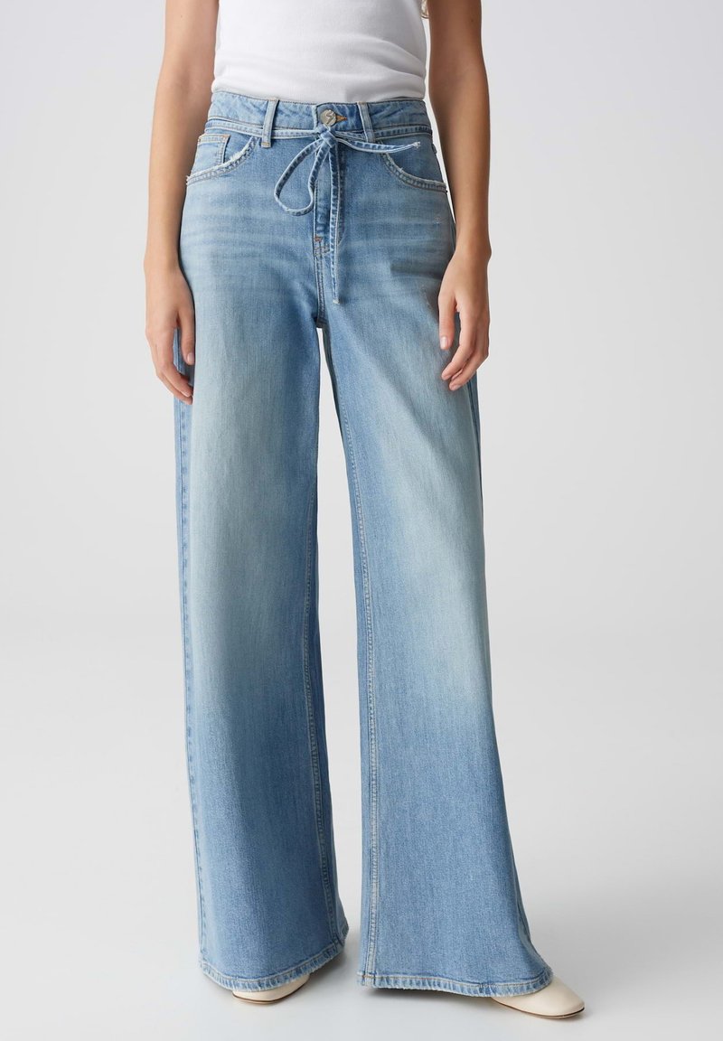 Lichtblauwe wijde jeans met een hoge taille, trekkoord en voorkruiden. Zachte denimtextuur met vervaging en een raw hem detail.