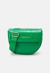 Grön axelväska i glänsande material, med ett präglat logomönster, rundad form och justerbar rem med guldiga detaljer.