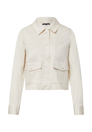 Przycięta beżowa kurtka z kołnierzem koszulowym, czterema przednimi kieszeniami i zapięciem na guziki; gładka faktura i prosty design.