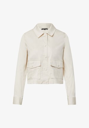 Przycięta beżowa kurtka z kołnierzem koszulowym, czterema przednimi kieszeniami i zapięciem na guziki; gładka faktura i prosty design.