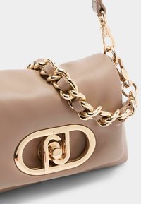 Beige lædertasker med en guld kædesti, der har en fremtrædende logo-lås og en glat overflade. Kompakt rektangulær form.