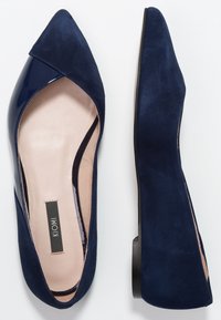 Granatowe baleriny z zaostrzonym noskiem, wykonane z kombinacji gładkiej lakierowanej skóry i zamszu. Posiadają niski obcas oraz miękką beżową wkładkę.