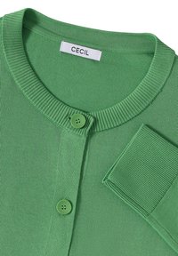 Zelený cardigan vyrobený z hladké pleteniny. Má žebrovaný límec a manžety, zapínání na jeden knoflík a značkovou etiketu "CECI."