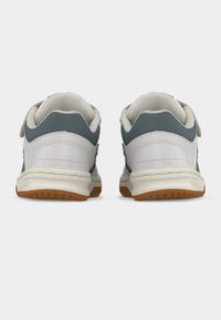 Ζευγάρι λευκών και γκρίζων αθλητικών παπουτσιών, που φαίνονται από πίσω, με επενδυμένους περιμετρικούς γιακάδες και καφέ ελαστικές σόλες, πάνω σε απλό φόντο.