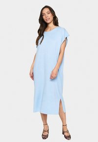 Abito azzurro chiaro, lungo fino al ginocchio, realizzato in tessuto morbido. Presenta maniche corte arrotolate, spacchi laterali e una vestibilità rilassata.