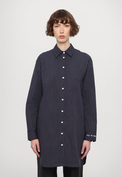 Button-up shirt in navy with vertical stripes, featuring a collar, long sleeves, a chest pocket, and embroidered detail on the cuff.
