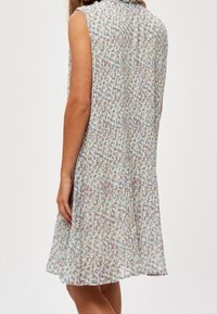 Vestido sin mangas de flores con un corte relajado, que presenta una tela ligera en colores pasteles, suaves plisados y un escote alto.