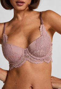 Lace bra in soft mauve with scalloped edges, underwire support, and adjustable straps. Features intricate floral lace detailing.