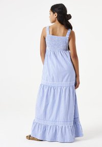 Gestreiftes Maxikleid in Blau und Weiß, mit einem gerafften Oberteil, breiten Trägern und einem Rüschensaum. Hergestellt aus leichtem Stoff.