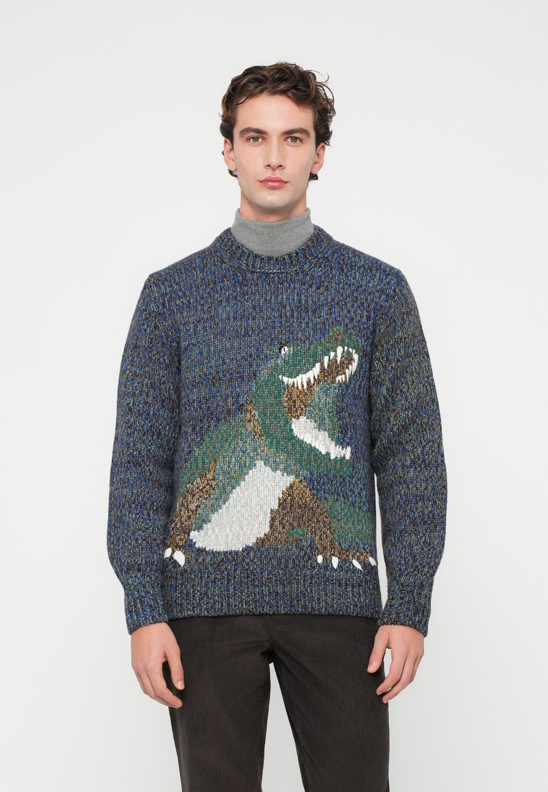 Pulover tricotat în nuanțe de albastru, cu un design de dinozaur în verde, brun și alb. Guler clasic rotund și mansete și tiv ribbate.