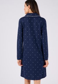 Abito da notte blu navy con maniche lunghe, caratterizzato da piccoli motivi a stella bianchi e un colletto, realizzato in tessuto morbido con una texture liscia.
