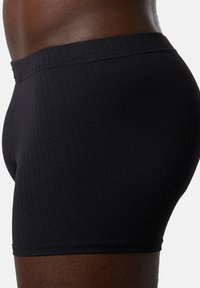 Sorte boxer shorts lavet af textured stof med et gittermønster. Elastisk talje med syede kanter. Tætsiddende design.