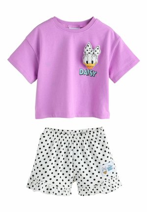 Fliederfarbenes Kurzarmshirt mit Daisy Duck Gesicht und Schriftzug, kombiniert mit weißen Shorts mit Polka-Dots, Rüschensaum und einem Daisy Duck Aufnäher.