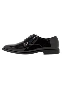 Chaussure de ville pour homme en cuir verni noir avec fermeture à lacets et talon bas empilé, présentée en profil latéral sur fond blanc.