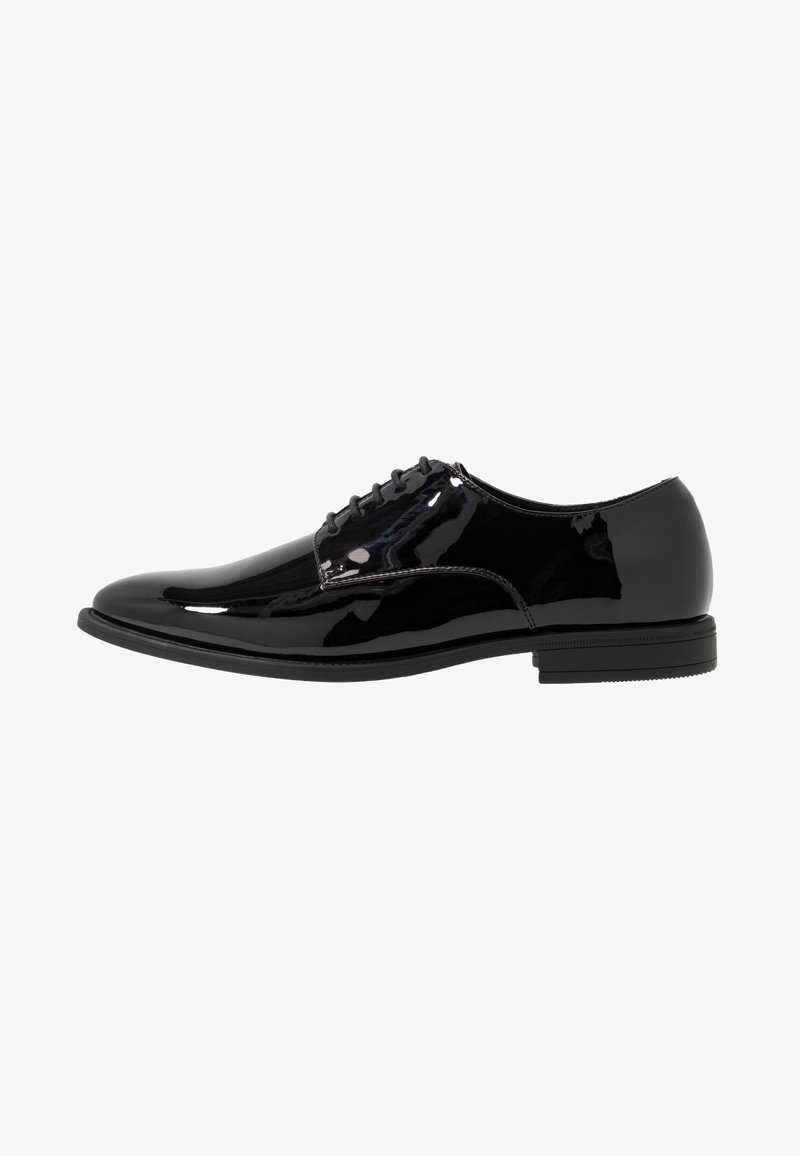 Chaussure de ville pour homme en cuir verni noir avec fermeture à lacets et talon bas empilé, présentée en profil latéral sur fond blanc.