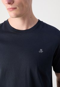Marine crew neck t-shirt lavet af bomuld. Har et lille hvidt broderet logo på venstre bryst. Glat tekstur, kortærmet.