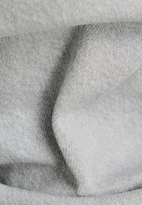 Textil gris con una superficie suave y ligeramente texturizada; tejido en un patrón de espiga, que muestra una profundidad sutil y una apariencia suave.