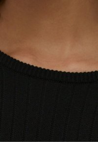 Col montant noir en tricot côtelé avec un col rond, présentant un motif texturé et un tissu doux au contact de la peau.