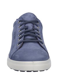 Tummansininen mokkasneakeri, jossa on valkoinen kumipohja, pyöreä kärki ja kuusi metallista reikää nauhoja varten. Ominaisuuksiin kuuluu teksturoitu pinta ja hillitty brändäys.