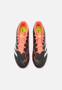 Scarpe da calcio nere con accenti e lacci arancione fluorescente. Presentano strisce bianche, suole interne perforate e un design elegante e aerodinamico.