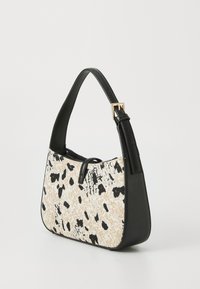 Black leather handbag with a contrasting beige fabric featuring a black spotted pattern. Includes a structured shape and adjustable strap.