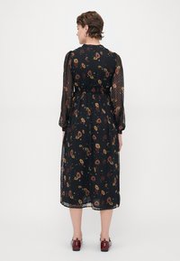Svart blomstermidikjole med gjennomsiktige, prikkede ermer. Har elastisk midje og levende blomsterdesign i rødt, gult og grønt.