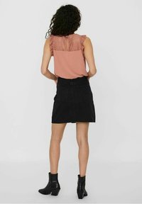 Raspberry pink sleeveless top with lace overlay and ruffled shoulders, paired with a black denim mini skirt and ankle boots.