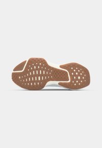 Sneaker outsole with a brown rubber grip pattern, featuring textured zones and subtle cutouts for traction, outlined by a white midsole.