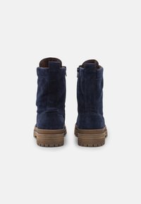 Bottes chelsea en suède marine avec une finition texturée, dotées d'une semelle en caoutchouc brun et de zips latéraux pour un enfilage facile.