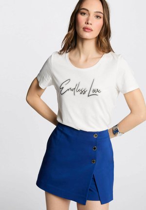 T-shirt bianco con la scritta "Endless Love", abbinato a una mini gonna blu con frontale a pattina e dettagli in bottone dorato.